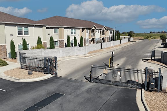 A gated entrance to a residential street with houses on either side.