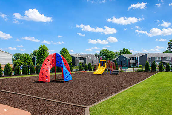 A playground with a red and blue slide and a yellow slide.