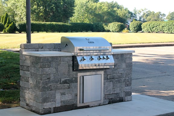 a stone outdoor kitchen with a grill at Indian Woods Apartments