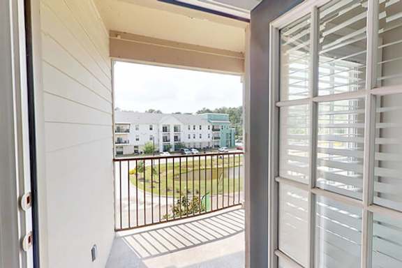 A view from a window looking out to a courtyard with a fence and houses in the distance.