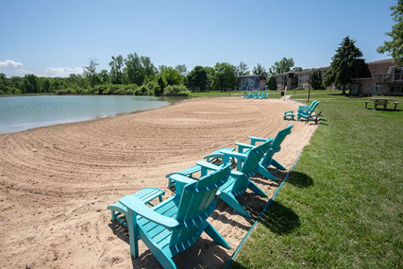 a row of blue beach chairs sitting on the shore of lambertonlake