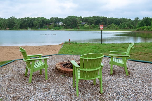 three green chairs sitting around a fire pit at lamberton lake apartments