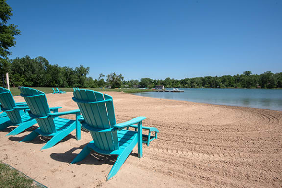 three blue beach chairs on the sand at lamberton lake apartment beach