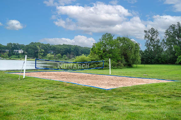 a volleyball court at lamberton lake apartments next to the lake