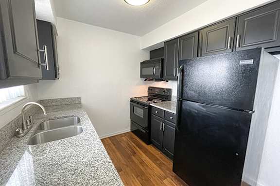 A kitchen with a black fridge, microwave, and stove.