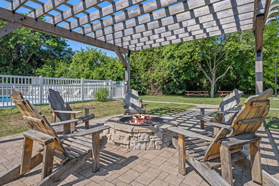 a patio with wooden chairs and a fire pit