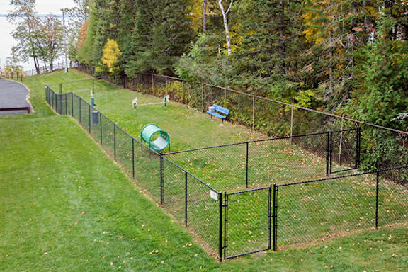 A green fence runs along a grassy hillside.