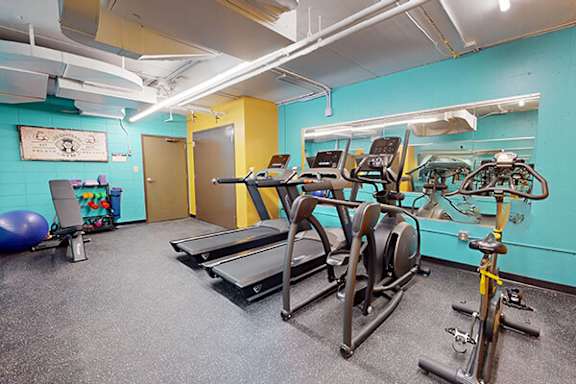 A gym with treadmills, exercise bikes, and a blue exercise ball.