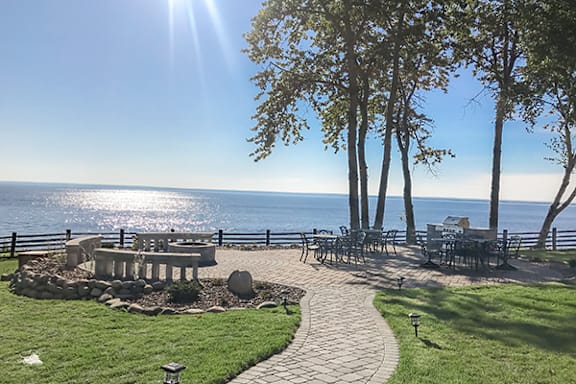 A sunny day at the beach with a picnic table and chairs.