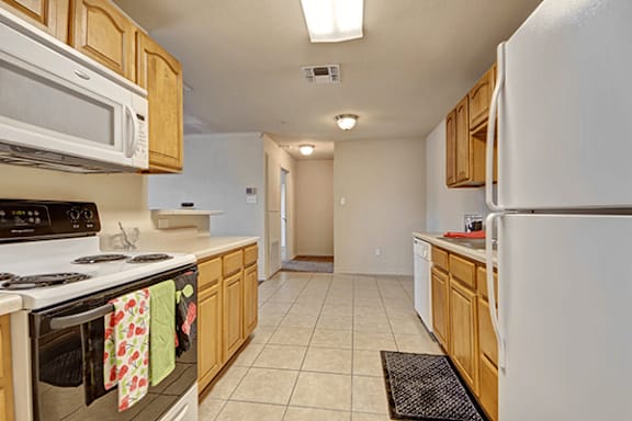 A kitchen with white appliances and wooden cabinets.