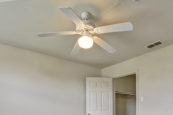 A white ceiling fan with a light is mounted in a room with a white door.