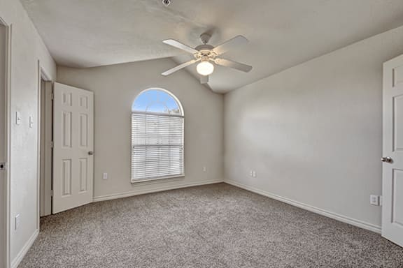 A room with a ceiling fan and a window with blinds.