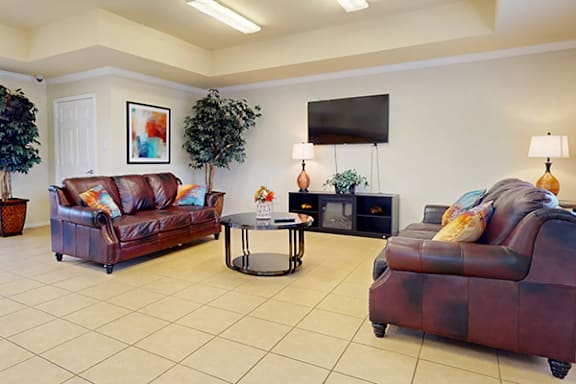 A living room with brown leather couches and a television mounted on the wall.