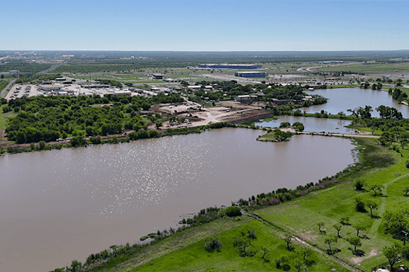 An aerial view of a flooded area with buildings and greenery.