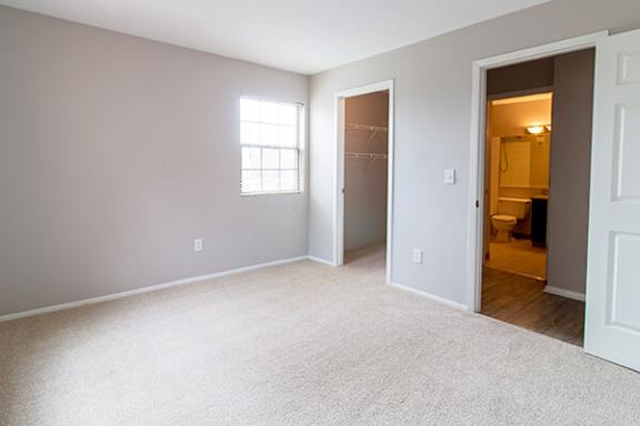 A room with a carpeted floor and a window.