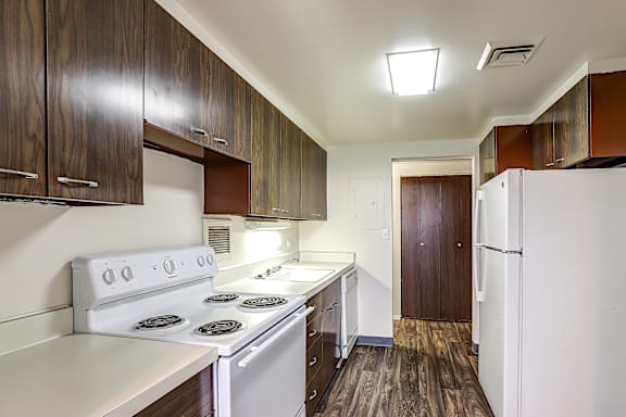 A kitchen with white appliances and wooden cabinets.