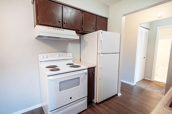 A white stove and refrigerator in a kitchen with brown cabinets.