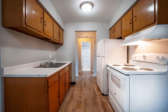 A kitchen with wooden cabinets and a white stove top oven.