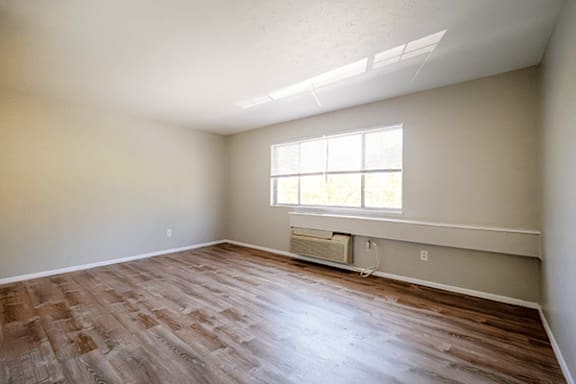 A room with a window and a wooden floor.