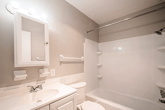 A white bathroom with a sink, mirror, and bathtub.