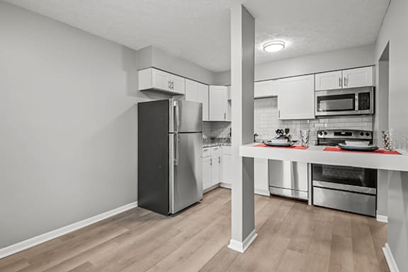 A kitchen with a refrigerator, oven, and microwave.