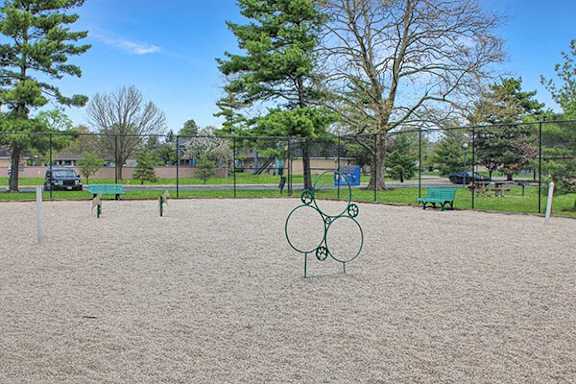 A playground with a sandy area and a green metal ring structure.