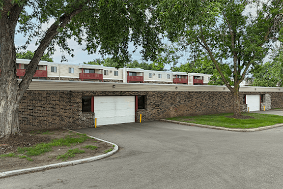 A tree is in front of a building with a white garage door.