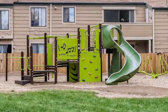 A playground with a green slide and a climbing frame.