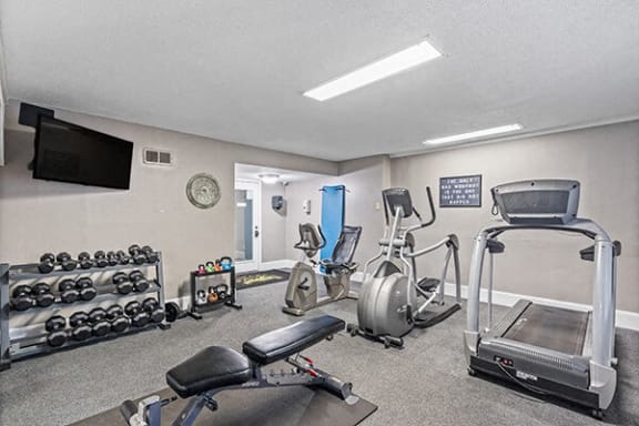 a gym with exercise equipment and a tv