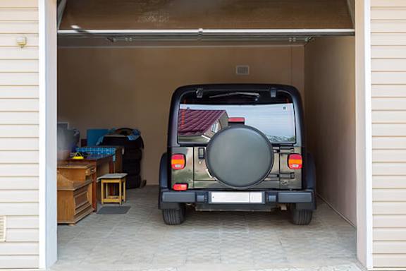 A black jeep is parked in a garage.