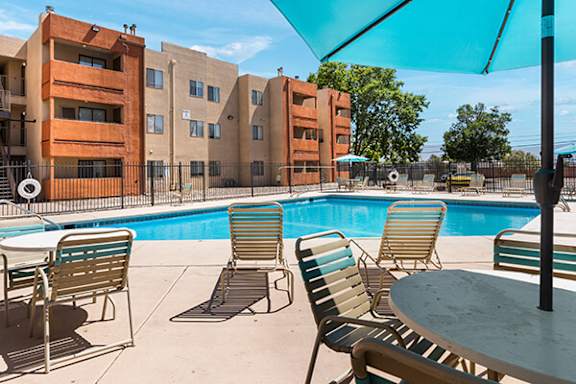 A pool area with chairs and a table.