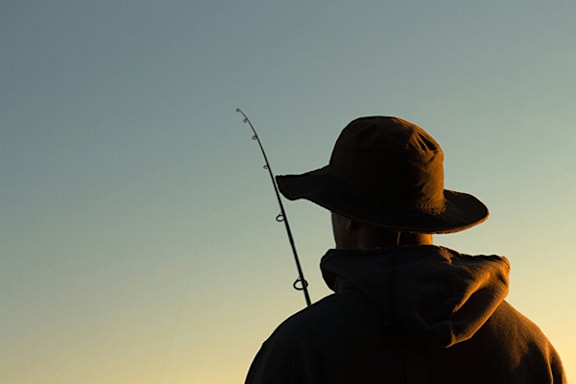 A man in a hat is fishing.