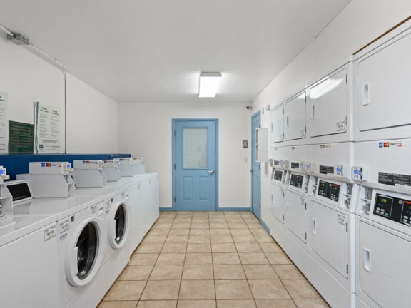 a laundry room with washers and dryers and a blue door