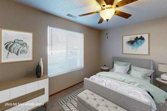 A bedroom with a bed, a ceiling fan, and two framed pictures on the wall.