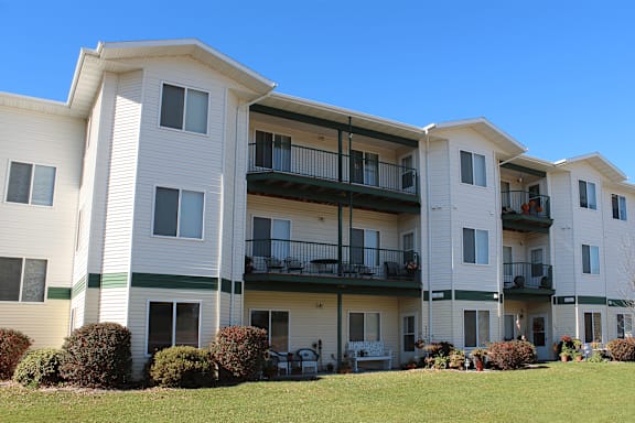 Apartment building with green bushes in front.