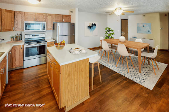 A kitchen with wooden cabinets and a wooden island with chairs around it.