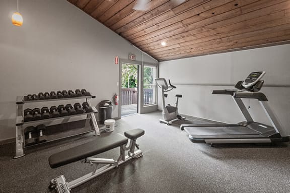 a gym with weights and chairs and a window