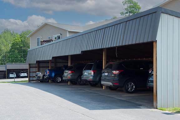A parking lot with cars parked under a metal roof.