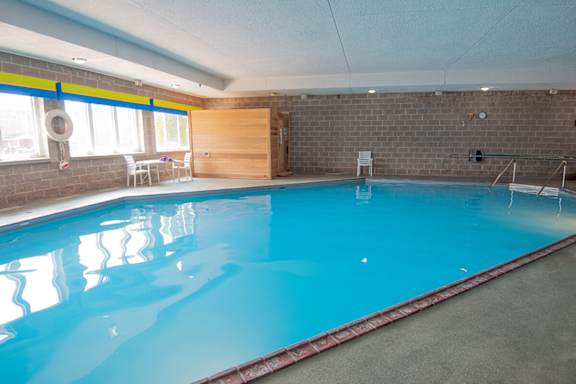 A large indoor swimming pool with a blue tinted water.