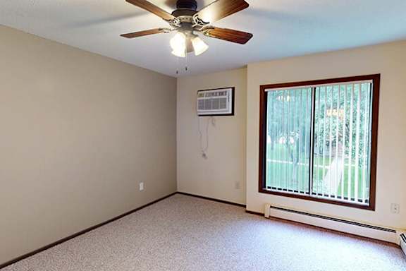 A room with a ceiling fan and a window with blinds.