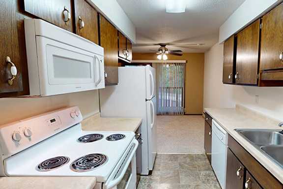 A kitchen with a white stove, microwave, and refrigerator.