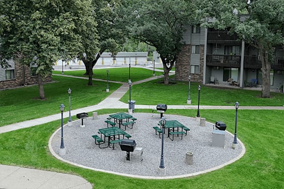 A round gravel patio with picnic tables and lampposts.