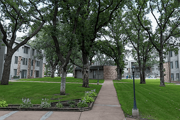 A tree-lined walkway leads to a building.