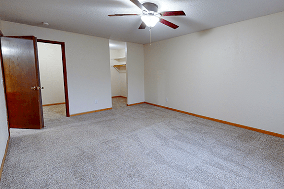 A room with a ceiling fan and carpeted floor.