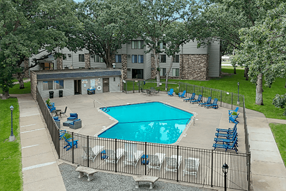 A pool surrounded by chairs and a fence.