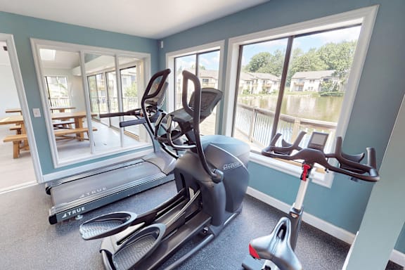 A room with a treadmill, exercise bike and a rowing machine.