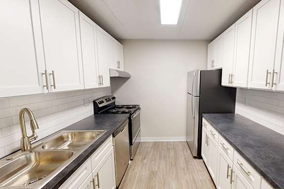 A kitchen with white cabinets and a black counter top with a stove.