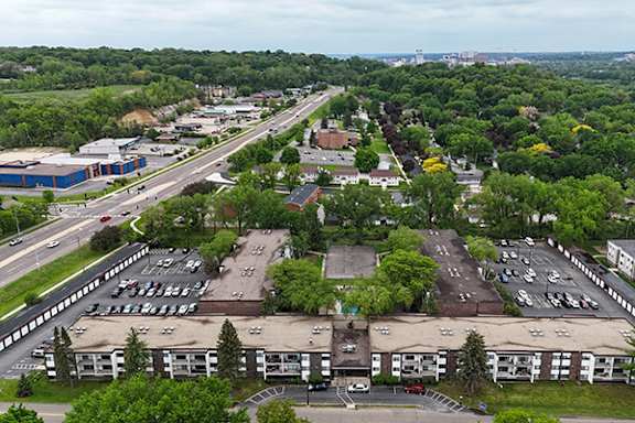 A parking lot is surrounded by trees and buildings.
