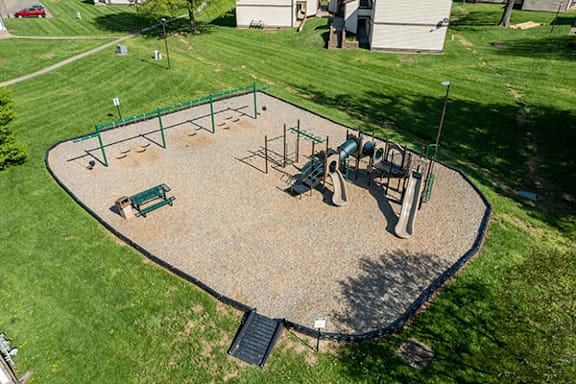 A playground with a green fence and a slide.