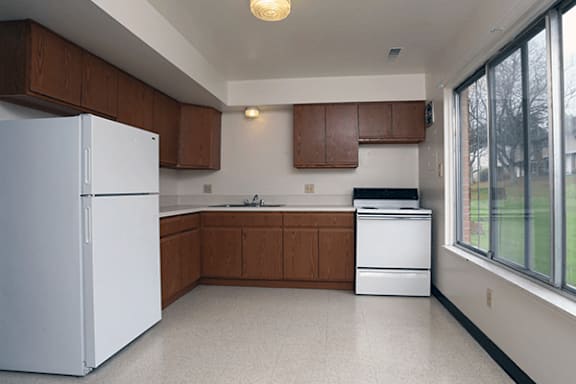 A kitchen with white appliances and brown cabinets.
